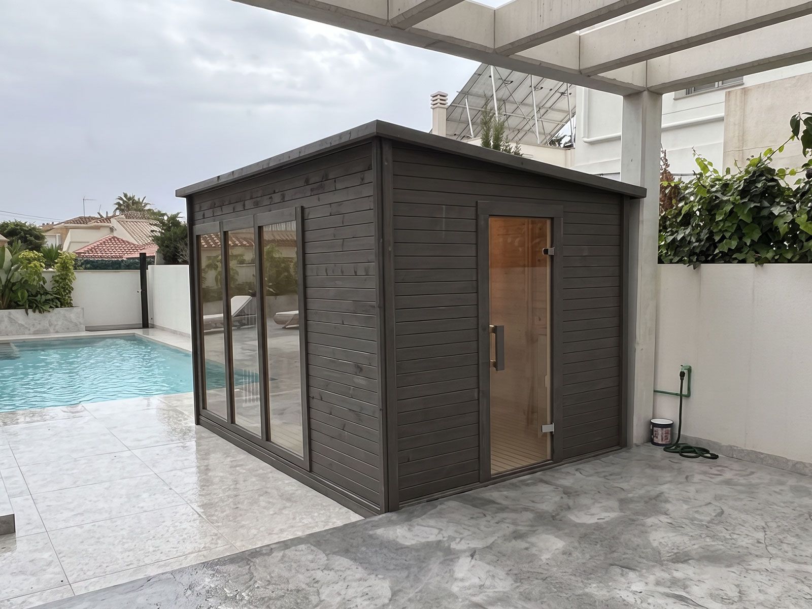 Sauna de exterior Saunakris instalada junto a una piscina residencial
