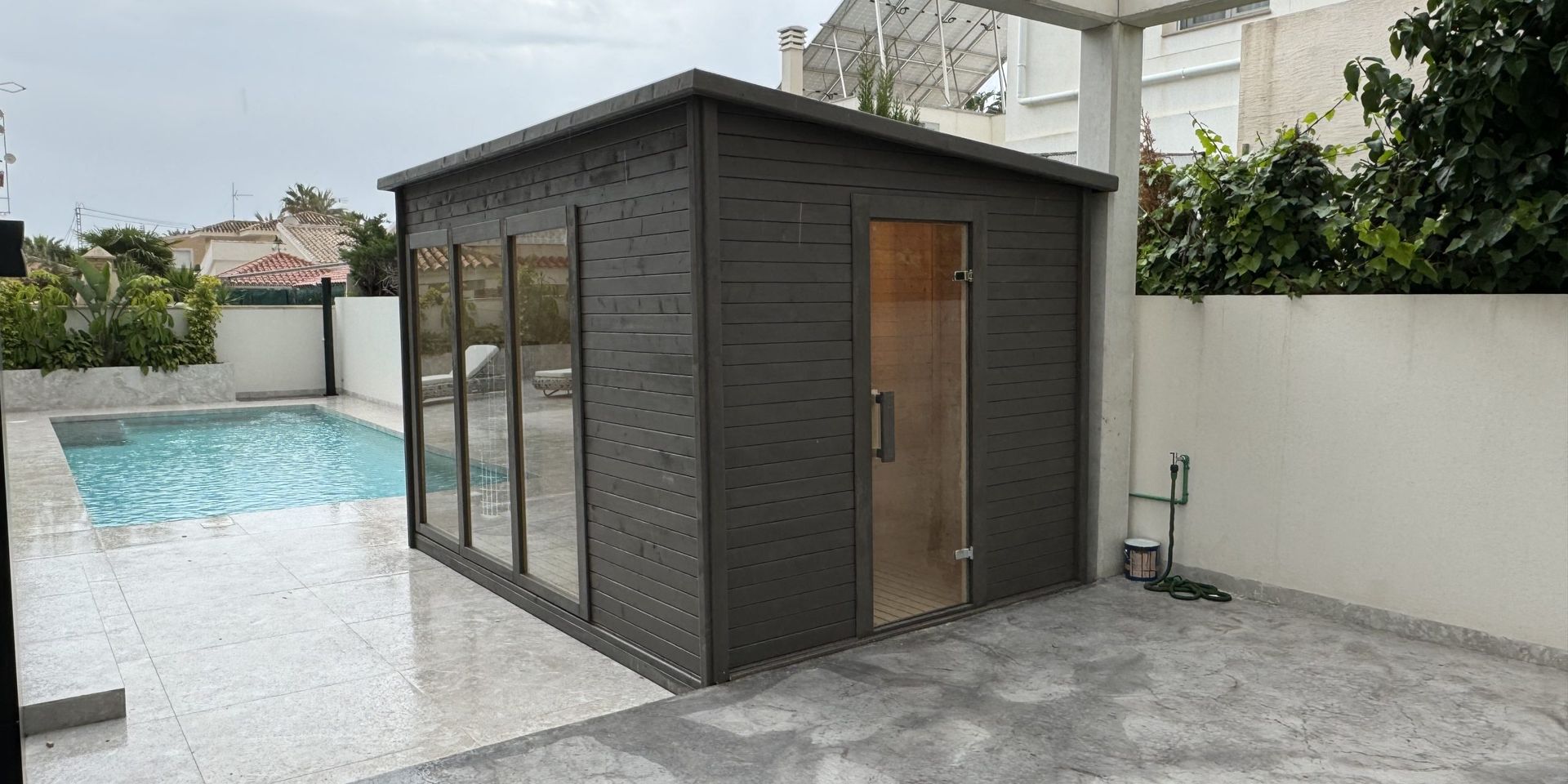 Sauna de exterior instalada junto a una piscina residencial