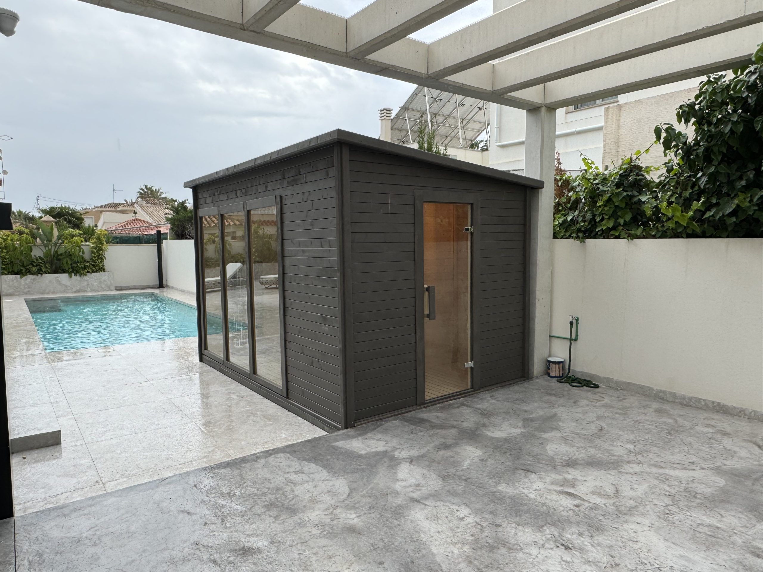 Sauna de exterior Saunakris instalada junto a una piscina