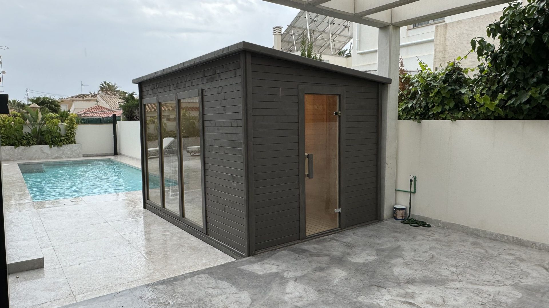 Sauna exterior oscura instalada junto a una piscina en Alicante