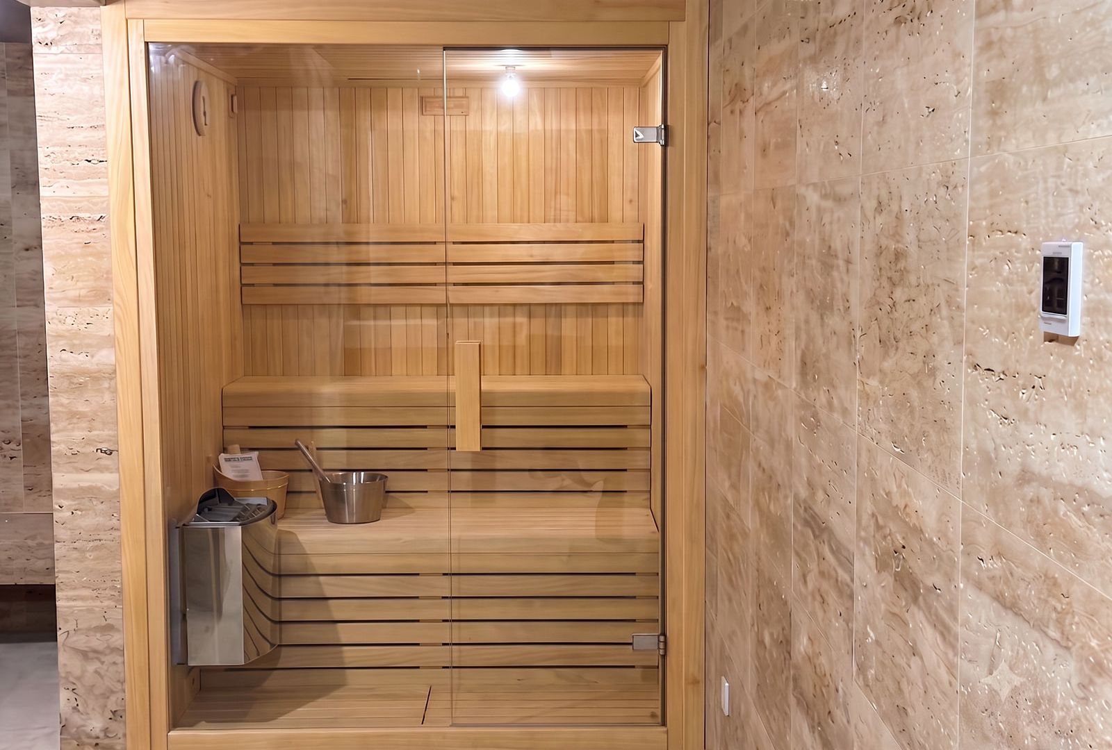 Sauna Olmo de interior integrada en un baño revestido de piedra